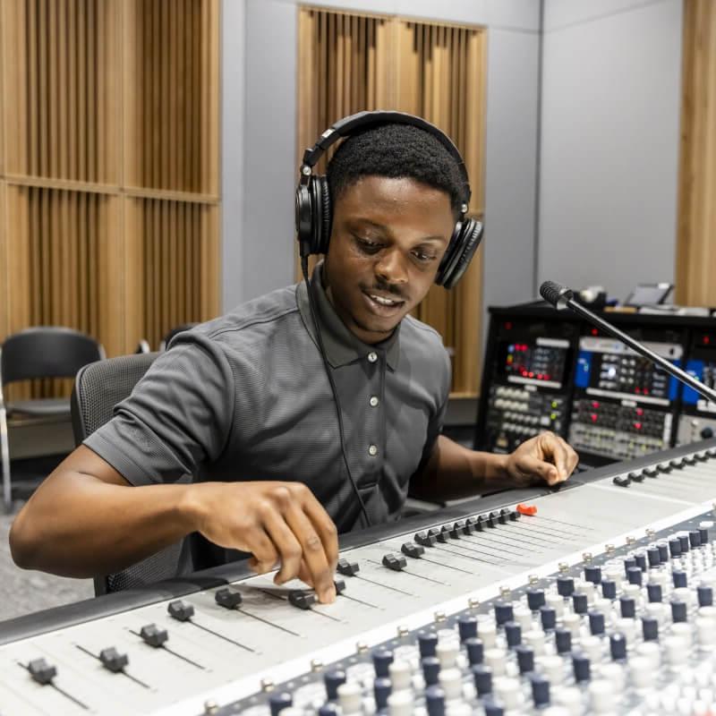 Person in a recording studio adjusting audio equipment.